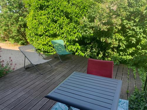 three chairs and a table on a wooden deck at La ferme d'aristide in Saillenard
