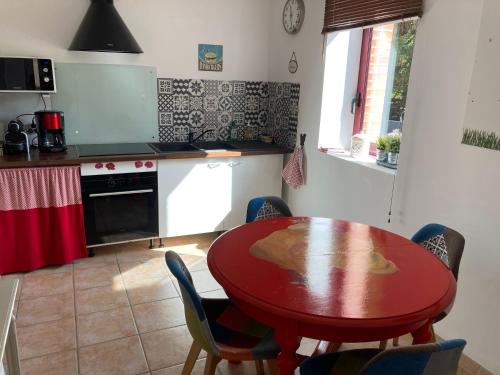 - une cuisine avec une table rouge et des chaises dans l'établissement Gite du Petit Tesseau, à Candé