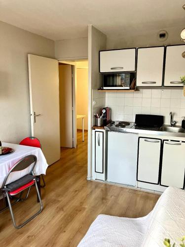 une cuisine avec des armoires blanches et une table dans une pièce dans l'établissement Appartement 2 pièces en étage élevé, centre-ville au calme, petite vue mer, à Nice