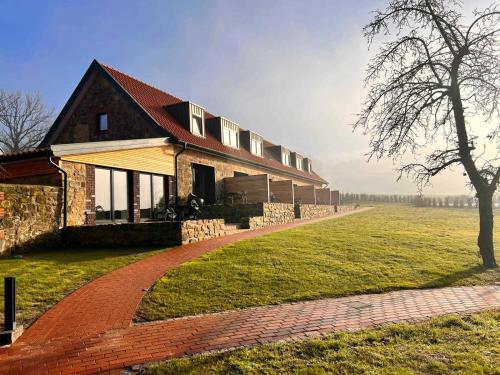 ein großes Haus mit einem Backsteinsteg neben einem Feld in der Unterkunft DRIEHOF Panorama Apartment (Apt. 9) in Tecklenburg