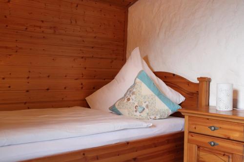 Una cama en una cabaña de madera con una almohada. en Ferienwohnungen Sternkopf, en Immenstadt im Allgäu