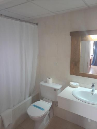 a white bathroom with a toilet and a sink at Cornucopia Hotel in Xagħra