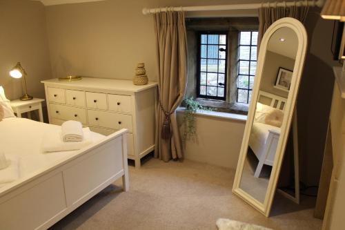 Schlafzimmer mit einem weißen Bett und einem Spiegel in der Unterkunft The Nook in Bakewell