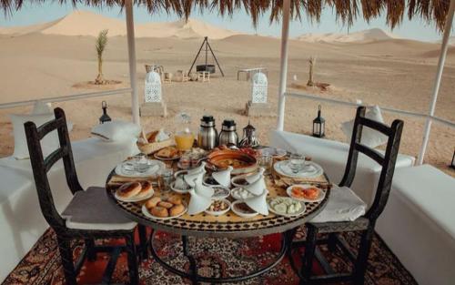 a table with food on it in the desert at Merzouga dreams Camp in Erfoud