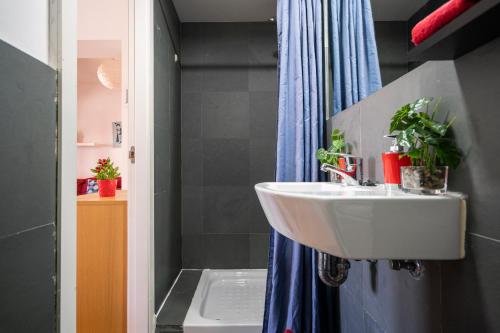 baño con lavabo y cortina de ducha azul en My City Home - Luminoso apartamento en Puerta del Ángel en Madrid