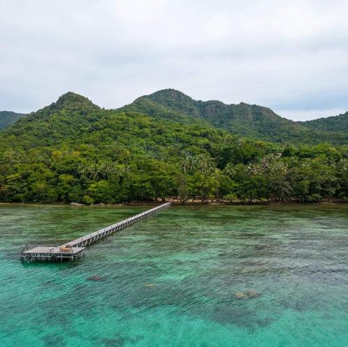 a dock in the water with mountains in the background at Alam Kita in Karimunjawa
