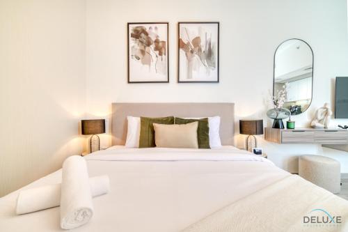 een witte slaapkamer met een groot bed en 2 spiegels bij Graceful Studio at Mesk 1 Midtown Dubai Production City by Deluxe Holiday Homes in Dubai