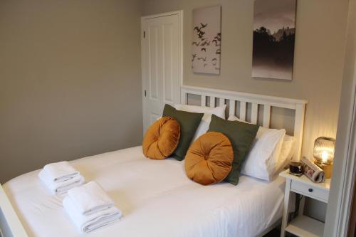 a white bed with two orange pillows on it at No4 Chapel Row in Bakewell