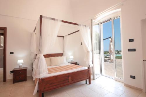 a bedroom with a canopy bed and a large window at Villa Dyria exclusive swimming pool in Monopoli
