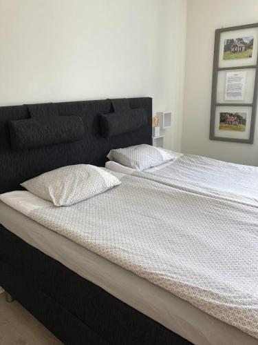 a large black bed with white sheets and pillows at Bergåsa bed & kitchen Drängsered in Torup