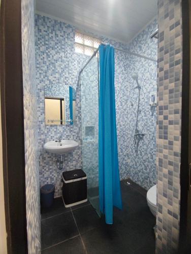 a bathroom with a blue shower curtain and a sink at 24StaycationHome in Kejayan