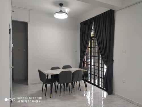 een eetkamer met een tafel en zwarte stoelen bij NEW 55 Homestay Corner Lot Spacious House in Bukit Bakri Muar in Muar