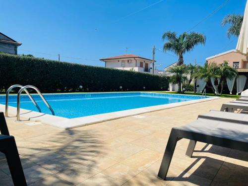 una piscina en un patio con palmeras en B&B Il Girasole, en Capo dʼOrlando