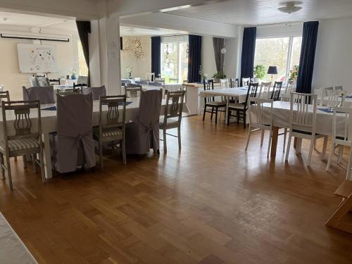 a dining room with white tables and chairs and tablesearcher at Bergåsa bed & kitchen Drängsered in Torup