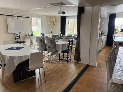 a dining room with white tables and chairs at Bergåsa bed & kitchen Drängsered in Torup
