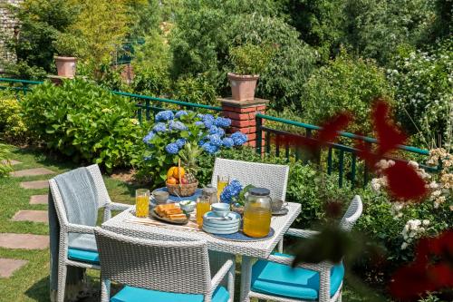 a table with food and drinks on it in a garden at SaffronStays Plaksha - 2BR pet-friendly homestay with Himalayan views, verandah dining & bonfire near Chauli ki Jali in Mukteshwar