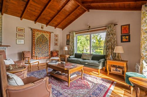 a living room with a couch and a table at SaffronStays Plaksha - 2BR pet-friendly homestay with Himalayan views, verandah dining & bonfire near Chauli ki Jali in Mukteshwar