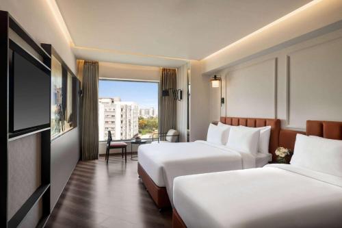 a hotel room with two beds and a television at Ramada Encore by Wyndham Indore Nipania in Indore