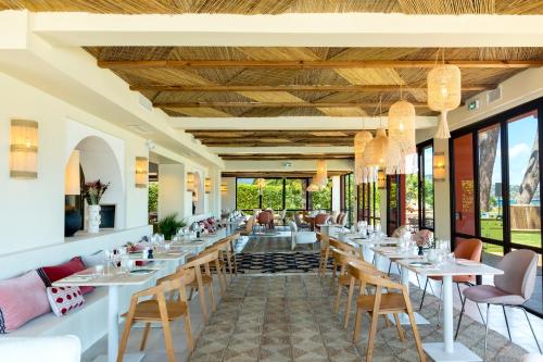 un restaurant avec des tables, des chaises et des fenêtres dans l'établissement Casa Santini x Roc Seven, à Porto-Vecchio