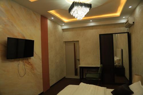 a bedroom with a tv on the wall and a bed at Green Hotel Dushanbe in Dushanbe