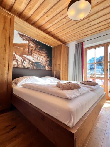 a large bed in a room with a large window at FIRSTpeak Appartements und Chalets in Zauchensee