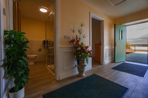 - une salle de bains avec un vase de fleurs dans le couloir dans l'établissement Carrig Island Lodge, à Ballylongford