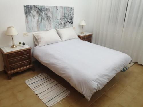 1 dormitorio con 1 cama blanca grande y 2 mesitas de noche en A CASA DOS AVÓS, en Celanova