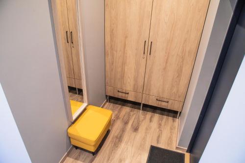 a small room with a yellow stool and cabinets at Closer to the Sea in Saulkrasti