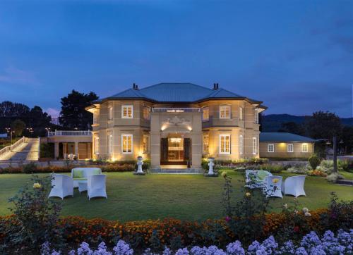a large house with white chairs in the yard at The Westbury Palace in Nuwara Eliya