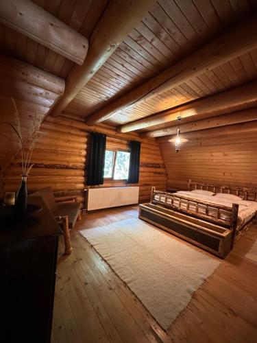 a large room with a bed in a log cabin at Après CHALET in Comandău