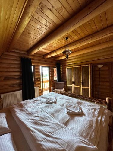 a large bed in a room with wooden walls at Après CHALET in Comandău