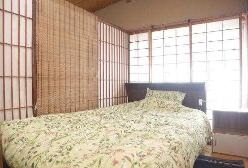 1 dormitorio con 1 cama con colcha de flores en Yamanouchi sekisan chi en Yokokura