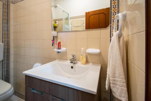 a bathroom with a sink and a toilet and a mirror at QuartosCotao in Agualva