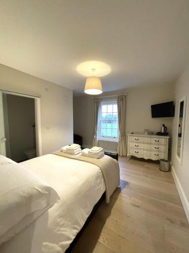 a bedroom with a large white bed and a dresser at Moulton Lawn House B&B in Moulton