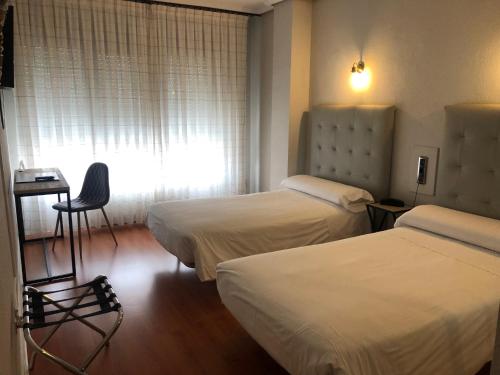a hotel room with two beds and a window at Hotel Marqués de Santillana in Torrelavega