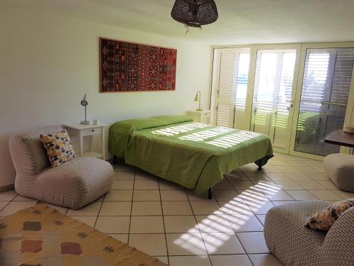 アウグスタにあるVilla al mare sulla scoglieraのベッドルーム1室(緑のベッド1台、椅子2脚付)