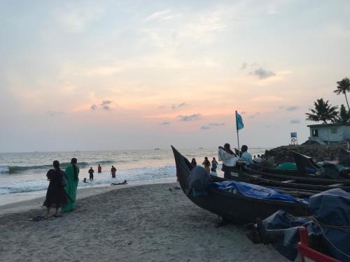 a group of people standing on a beach with two boats at Gods own home stay in Cochin