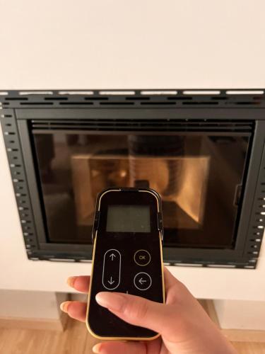 a person holding a cell phone in front of a microwave at L’Arco sul Lago • Gold Apartment in Castro