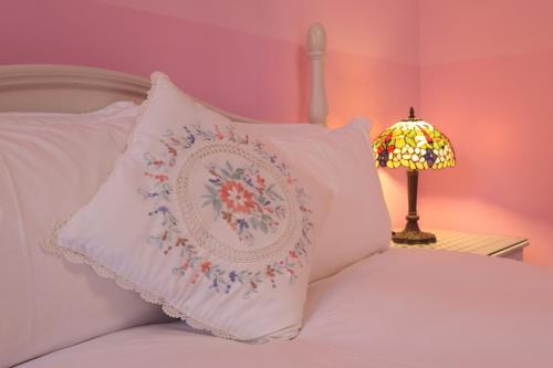 a bed with white pillows and a lamp and a pillow with a flower pattern at 干城小鎮民宿-包棟-寵物友善 in Jian