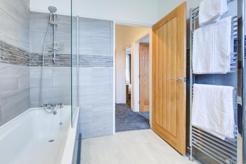 a bathroom with a tub and a shower with a glass door at Pass the Keys Beautiful House in SouthChurch in Southend-on-Sea