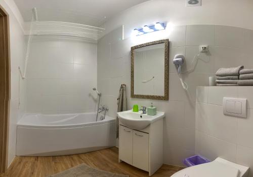 a white bathroom with a tub sink and a mirror at Wilanowska in Giżycko