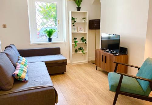 a living room with a couch and a flat screen tv at Beautiful Two Bedroom Cottage in Morriston