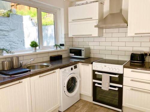 a kitchen with a sink and a washing machine at Beautiful Two Bedroom Cottage in Morriston