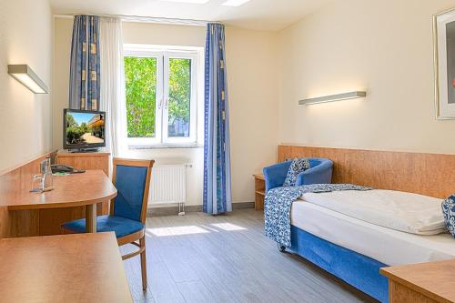 a hotel room with a bed and a desk and a table at Hotel Am Moosfeld in Munich