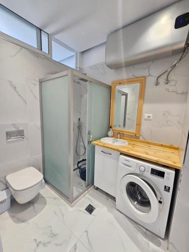 a bathroom with a washing machine and a toilet at Amazing Sea View Apartment in Sarandë