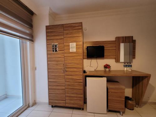 a room with a desk and a cabinet with a television at Araucaria Pension in Antalya