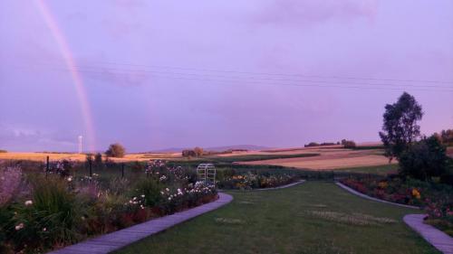 un arco iris en el cielo sobre un jardín con flores en Cztery Pory Roku pokoje z łazienkami do wynajęcia, en Osiek