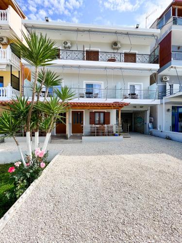 a large white building with palm trees in front of it at Ionian View B&B in Himare