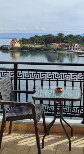 a table and chair on a balcony with a view of the water at l' atoll d' Helene in Gythio