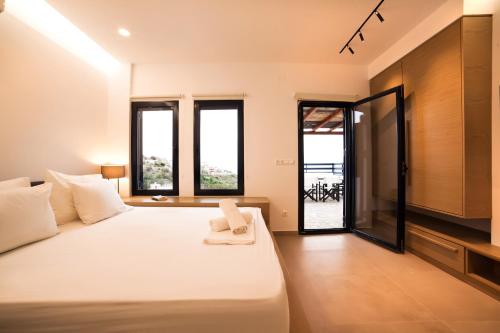 ein Schlafzimmer mit einem großen weißen Bett und einigen Fenstern in der Unterkunft Blue Dawn Kalymnos in Kalymnos